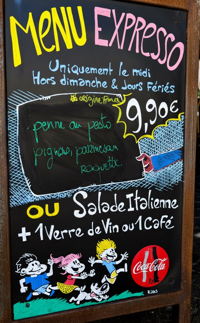 Panneau en bois 'Plat du jour' avec illustration colorée d'un cuisinier et d'un cochon.