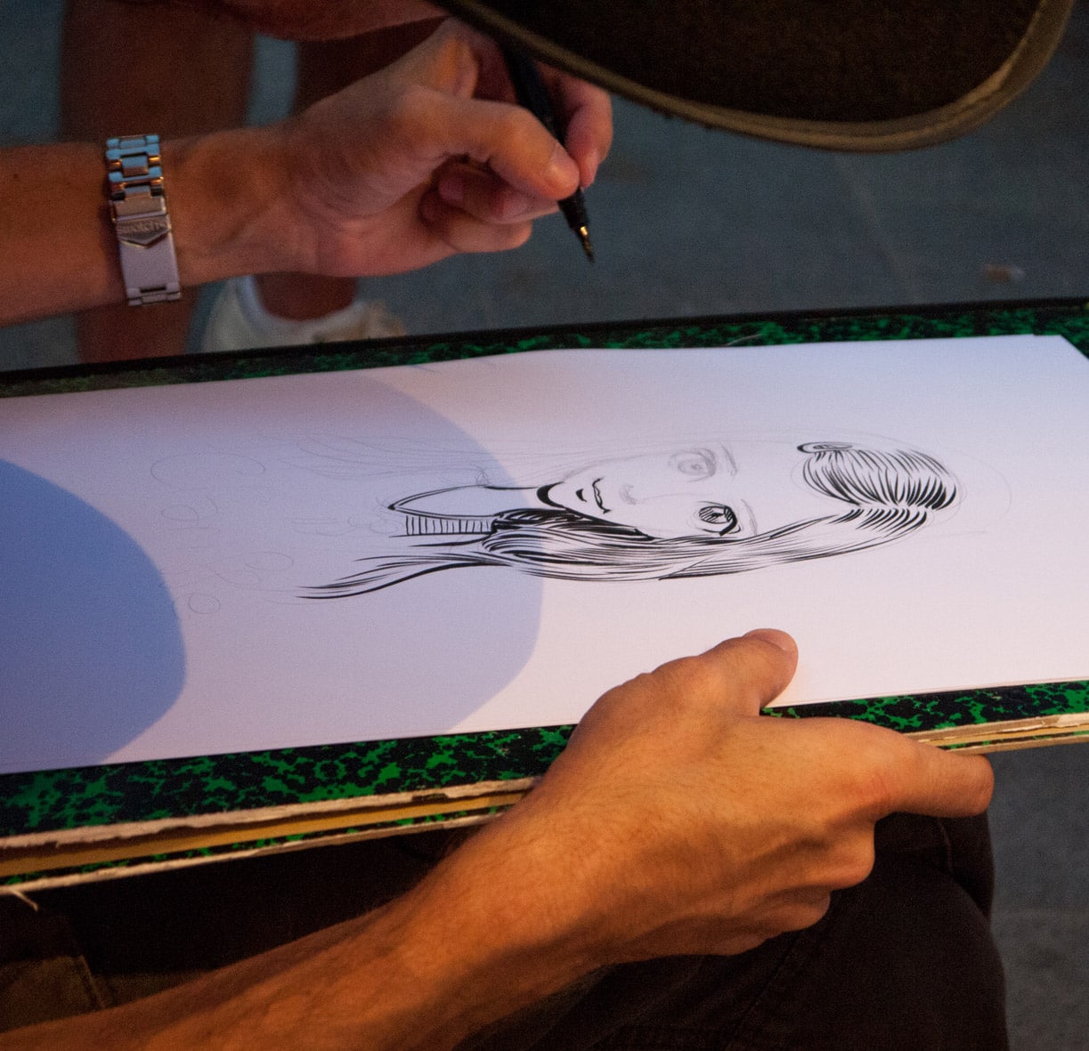 Gros plan sur la main de Sébastien Rieu dessinant un portrait à l'encre de Chine, Arcachon