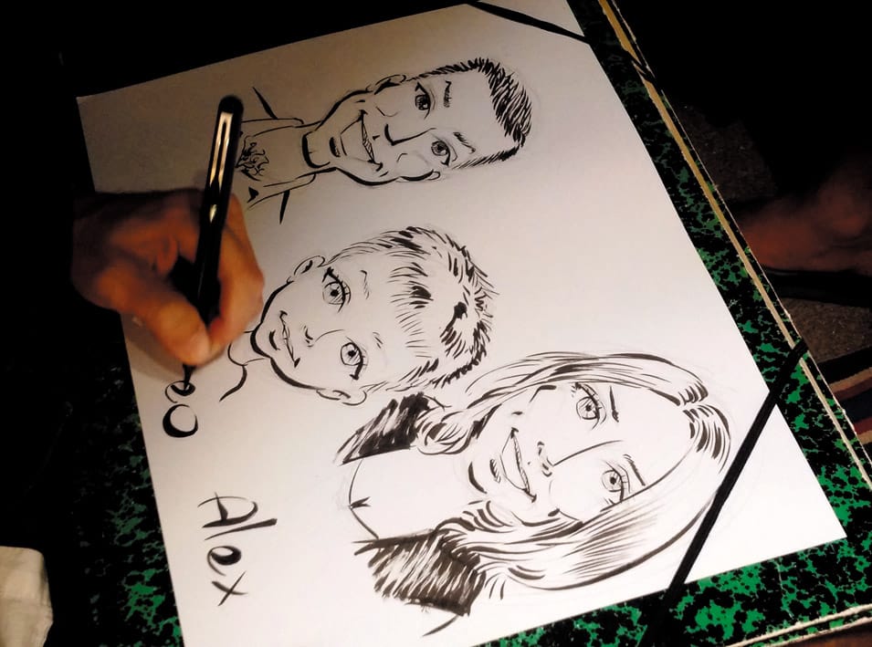Gros plan sur la main de Sébastien Rieu dessinant un portrait de famille à l'encre, jetée Thiers, Arcachon