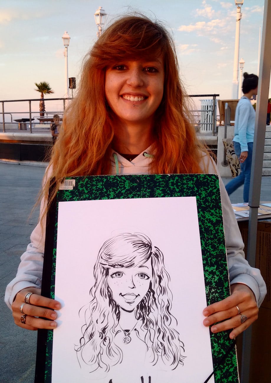 Jeune femme rousse souriante posant avec son portrait illustré sur la jetée Thiers à Arcachon