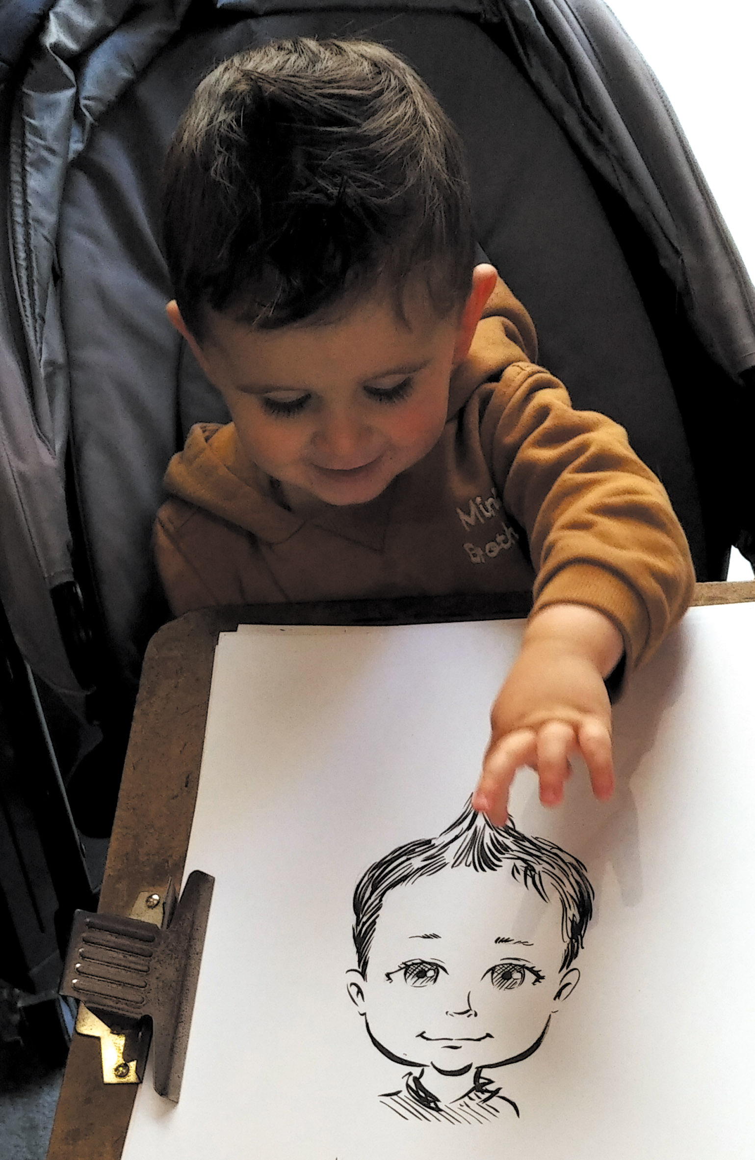 Un jeune enfant découvre et touche son portrait dessiné sur papier