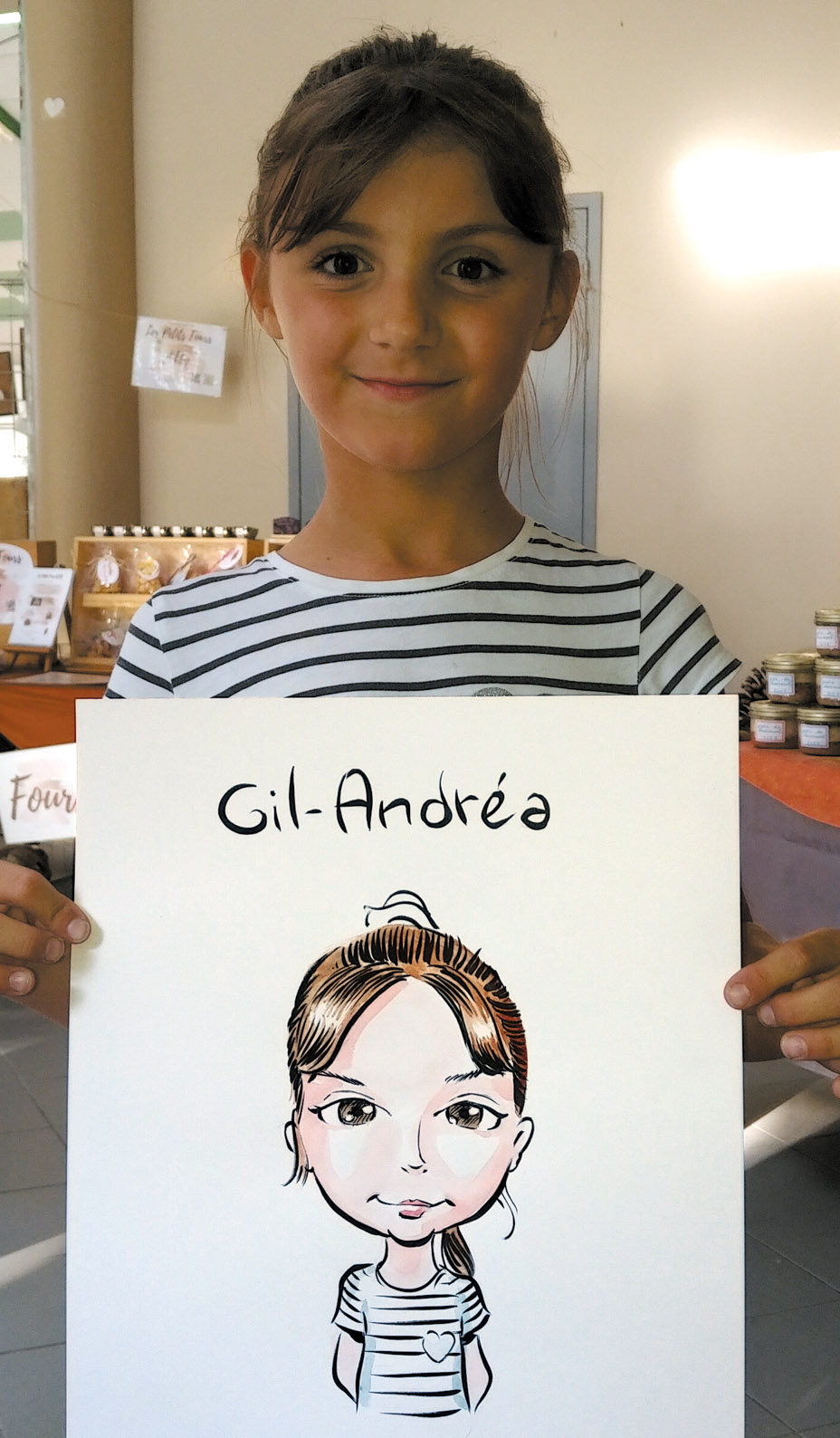 Une fillette en marinière présente son portrait dessiné en couleur